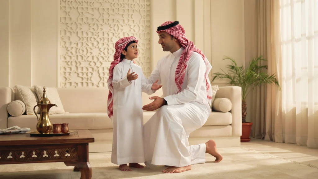أب سعودي يستمع لطفله باهتمام في مجلس البيت كنموذج لتعزيز الاستقلالية للأطفال من خلال الحوار